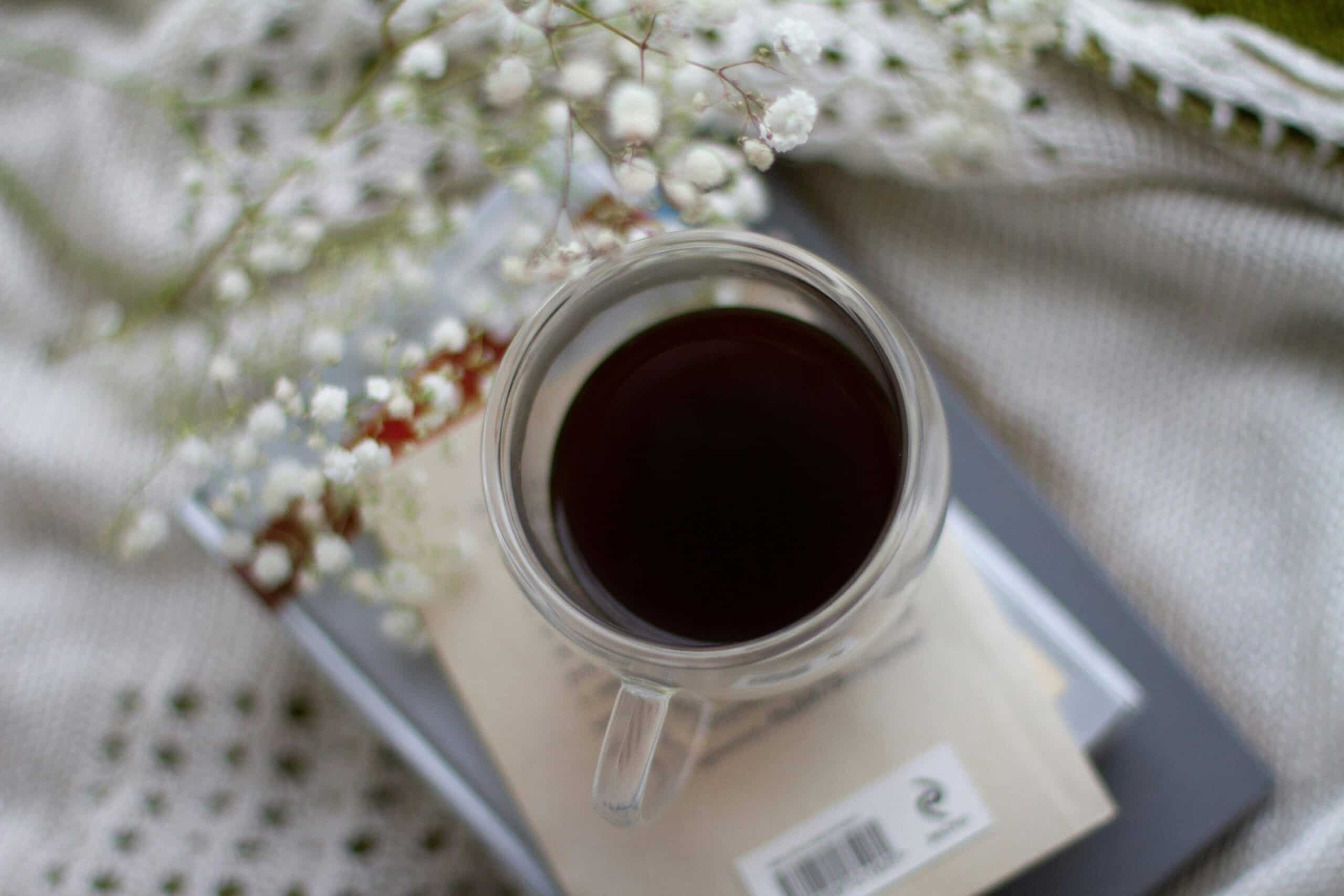 Cozy flat lay of a coffee mug with books and flowers, creating a relaxed atmosphere.