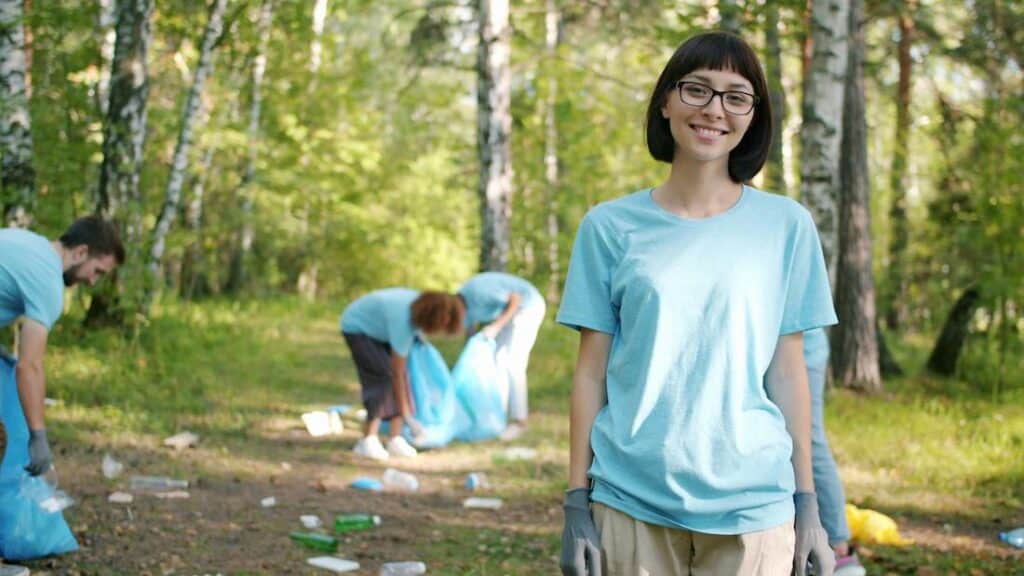 team-building-ecologique-1 Femme souriant pendant que les gens nettoient les déchets de la forêt